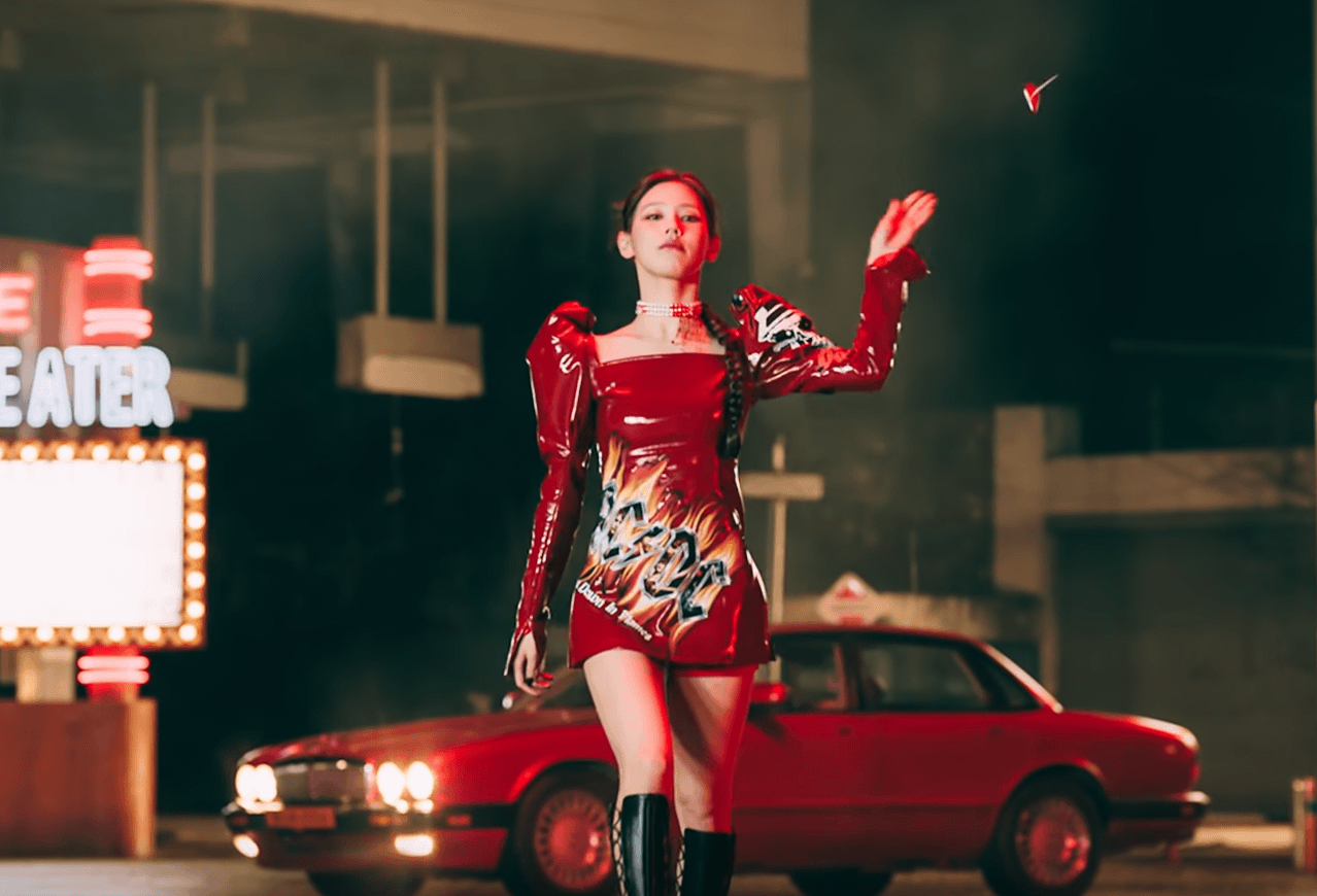 Miyeon porte une veste avec Slayer sur la manche et Ac/DC sur sa jupe. Elle jette une sucette en l'air