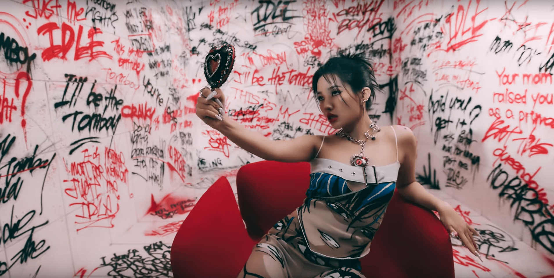 Soyeon, avec un imprimé manga, dans une pièce aux murs taggués de rouge et de noir