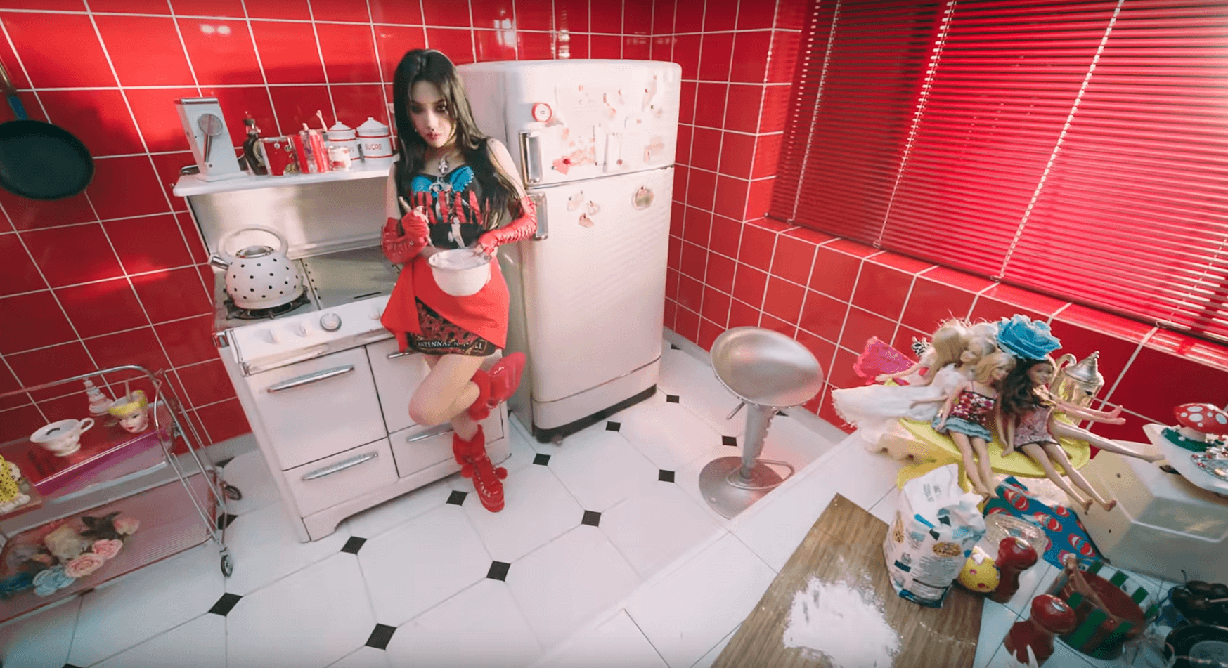 Soyeon, scène dans la cuisine, où elle porte un top Nirvana et une jupe Slipknot
