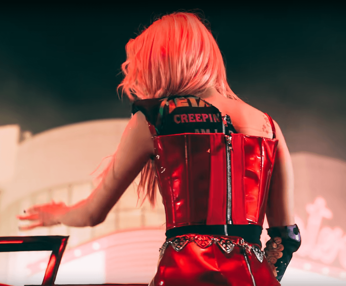 Yuqi, de dos, port un t-shirt Metallica sous un corset rouge