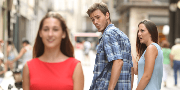 en arrière plan, un couple se tient la main mais l'homme se retourne pour regarder une jeune femme en rouge au premier plan. la compagne de l'homme a une expression dégoûtée